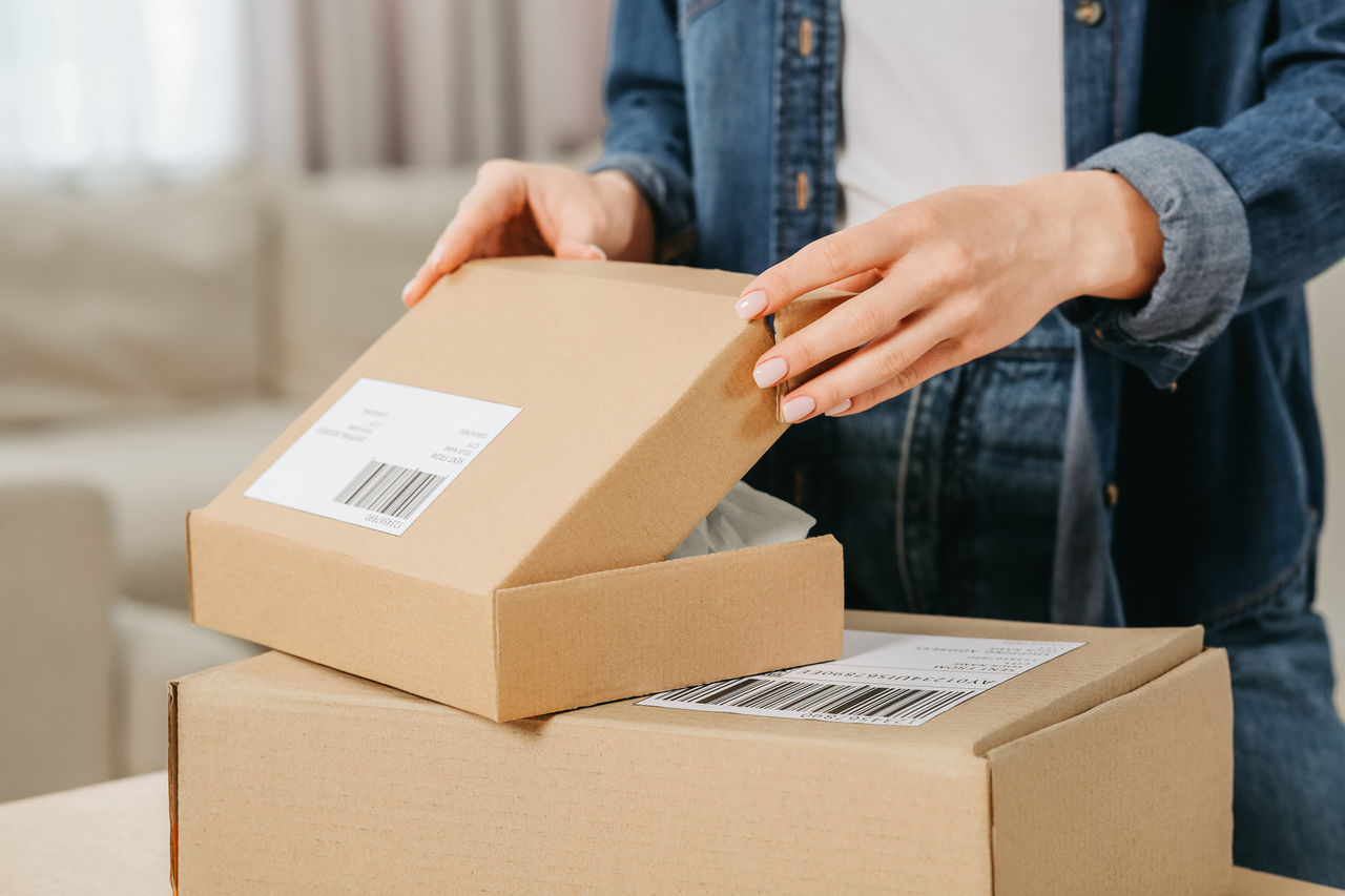 Woman unpacking parcel at home, closeup. Online store