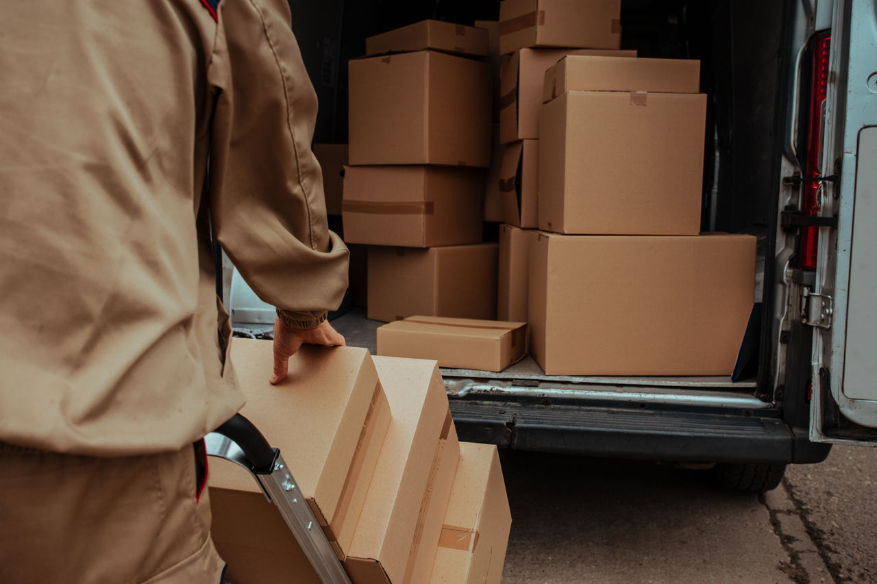 Courier packing cardboard boxes in van and preparing for delivering