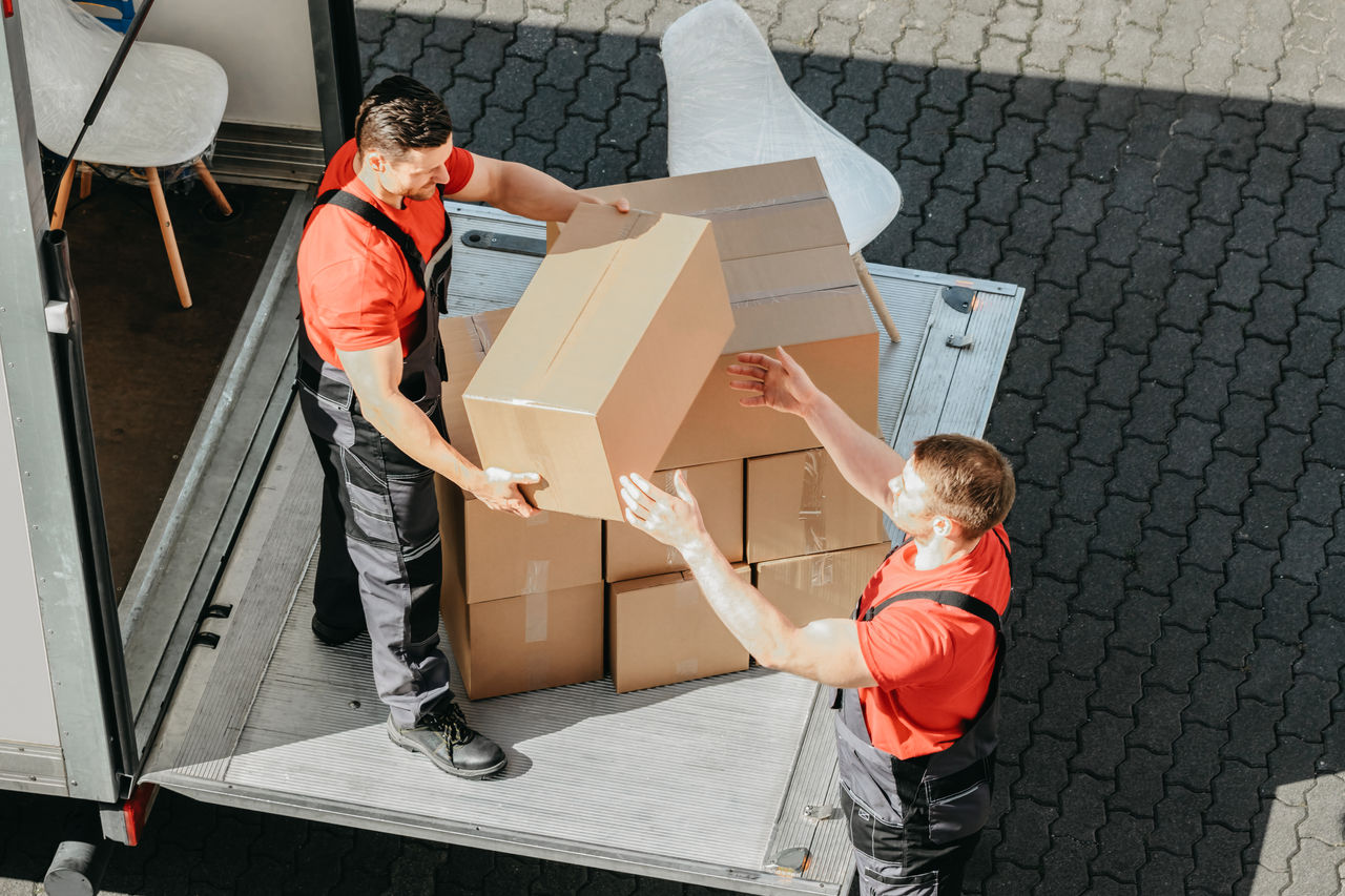 An Overhead View Of A Male Movers Unloading The Cardboard Boxes Form Truck On Street